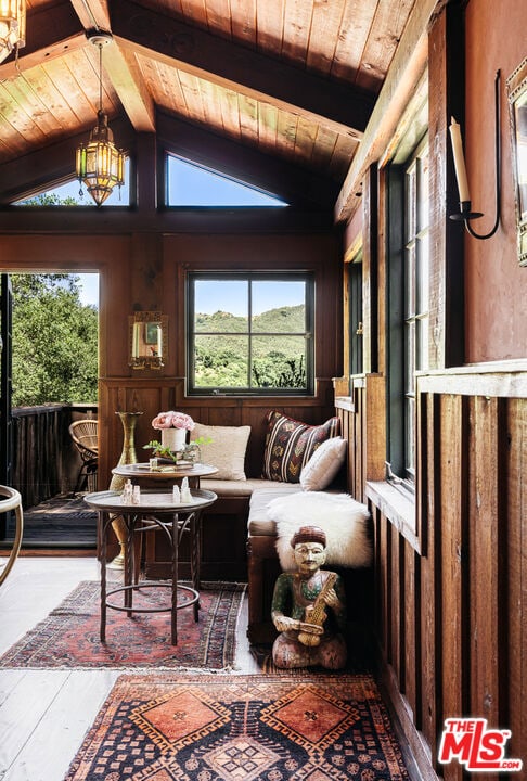 sunroom featuring vaulted ceiling with beams, breakfast area, and wooden ceiling