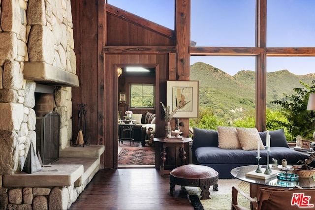 living room featuring a mountain view, wood walls, a towering ceiling, and dark hardwood / wood-style flooring