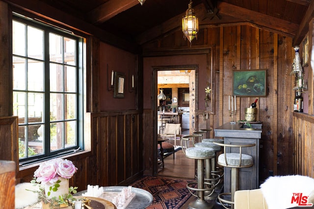 interior space featuring lofted ceiling with beams, wooden walls, and plenty of natural light