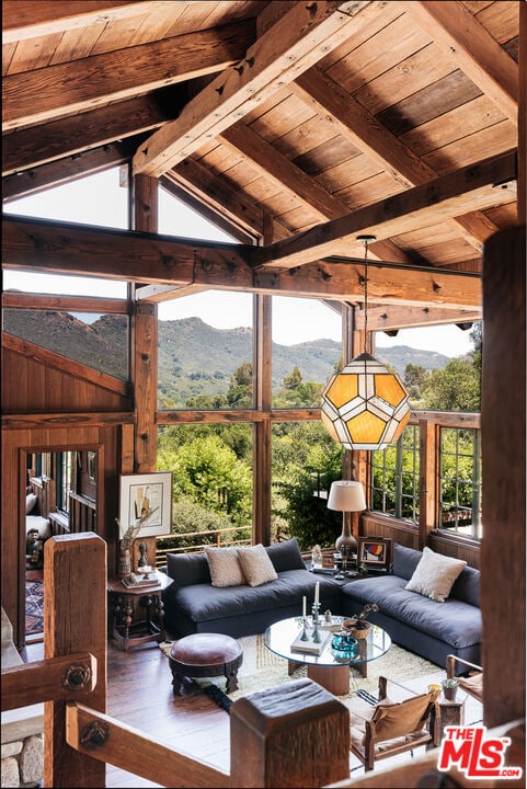 living room with a mountain view, wood-type flooring, wood ceiling, and vaulted ceiling with beams