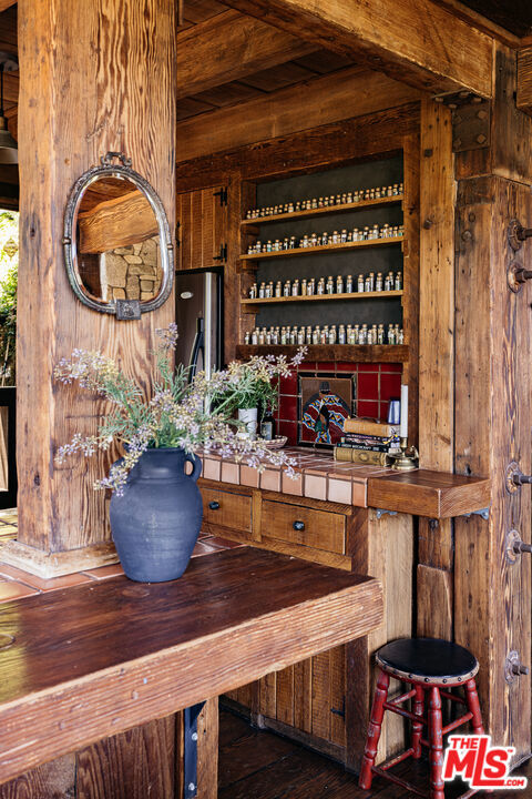 bar featuring tile countertops, stainless steel fridge, wooden walls, and dark wood-type flooring