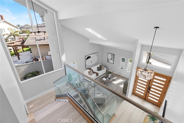 interior space featuring vaulted ceiling with skylight, an inviting chandelier, and hardwood / wood-style floors