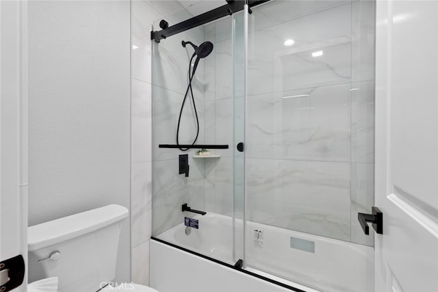 bathroom featuring toilet and bath / shower combo with glass door