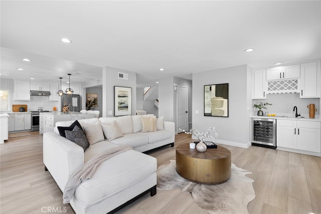 living room with wine cooler, light hardwood / wood-style flooring, and wet bar