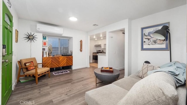 living area with visible vents, wood finished floors, baseboards, a wall mounted air conditioner, and recessed lighting