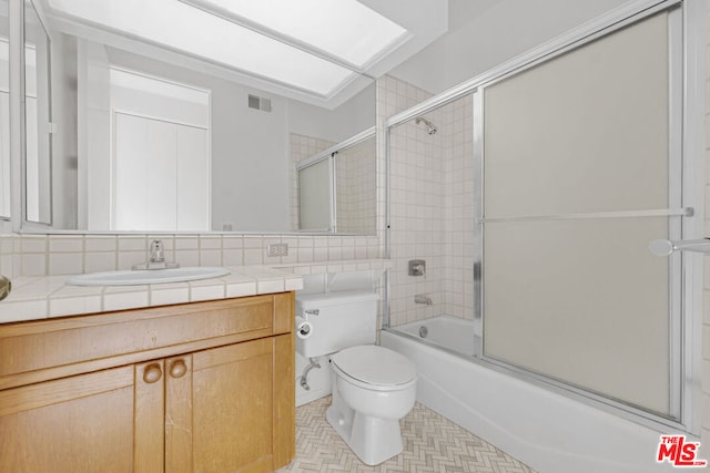 full bathroom with decorative backsplash, toilet, bath / shower combo with glass door, and vanity