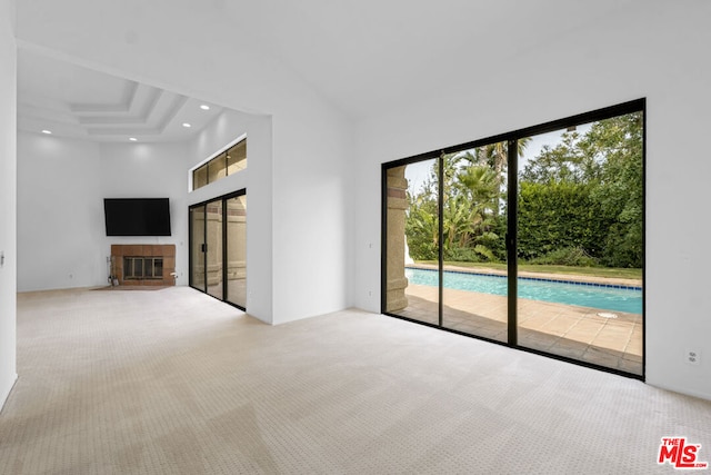 unfurnished living room with carpet flooring, a high ceiling, and a tile fireplace