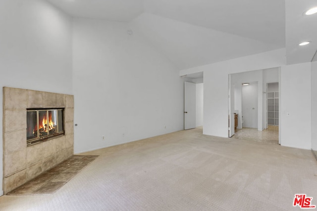 unfurnished living room with light colored carpet, lofted ceiling, and a tile fireplace