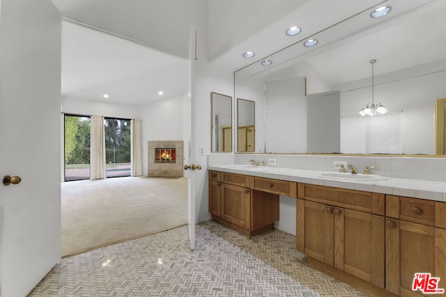 bathroom with a tiled fireplace, vanity, and a notable chandelier