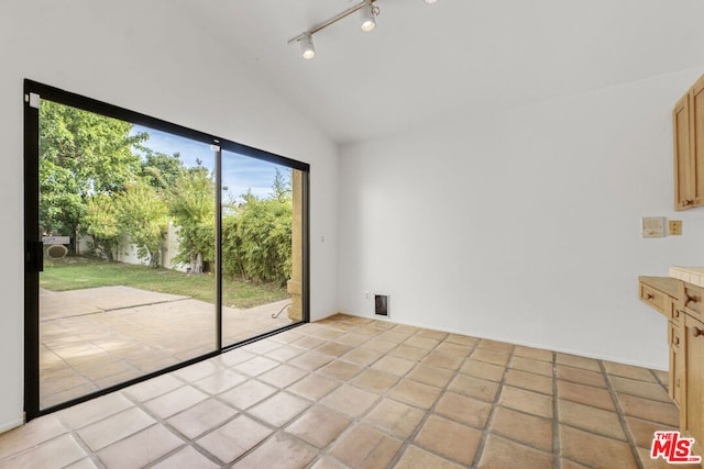 spare room with light tile patterned flooring, rail lighting, and vaulted ceiling