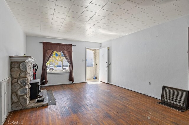 unfurnished living room featuring a wood stove and dark hardwood / wood-style floors