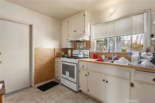 kitchen featuring white range with gas cooktop, white cabinetry, and sink