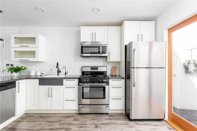 kitchen with light hardwood / wood-style flooring, sink, white cabinets, tasteful backsplash, and stainless steel appliances