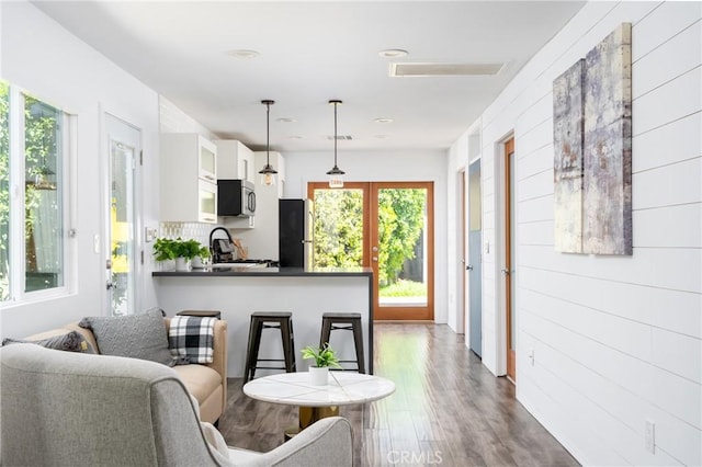 kitchen with wood-type flooring, kitchen peninsula, hanging light fixtures, appliances with stainless steel finishes, and white cabinetry