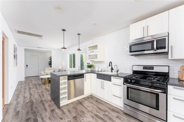 kitchen with white cabinets, stainless steel appliances, and decorative light fixtures