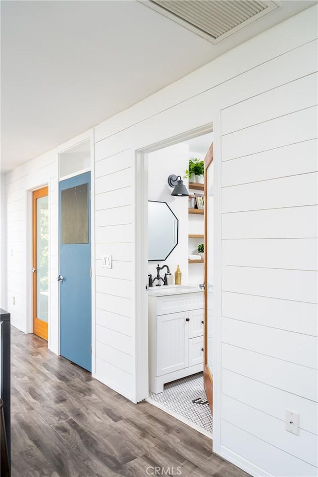 hall with sink, wood walls, and dark wood-type flooring