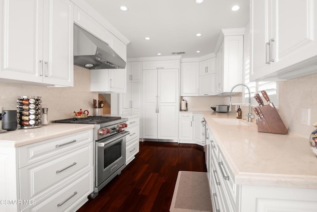 kitchen featuring dark wood-type flooring, luxury range, sink, white cabinetry, and extractor fan