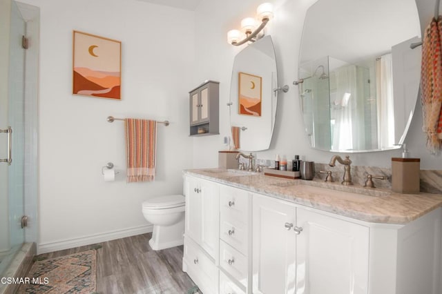 bathroom with hardwood / wood-style floors, vanity, toilet, and a shower with shower door