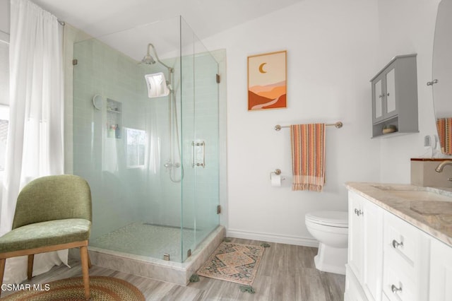 bathroom featuring hardwood / wood-style floors, vanity, toilet, and a shower with door