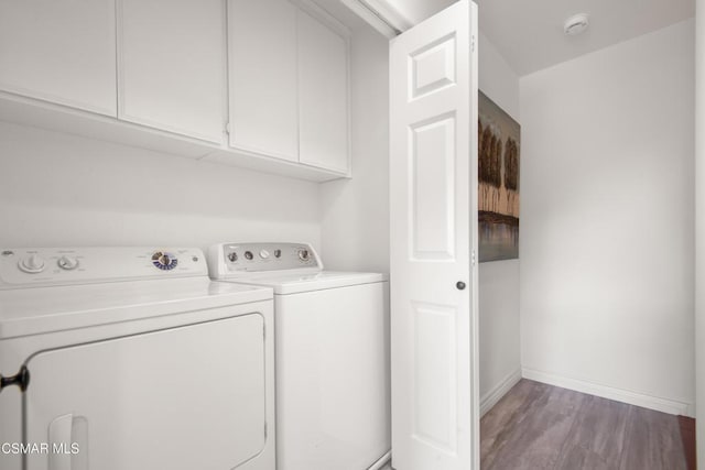 laundry room featuring cabinets, washing machine and dryer, and hardwood / wood-style flooring