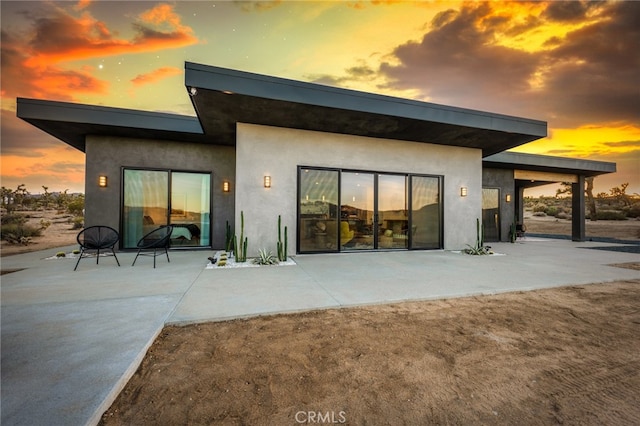 back house at dusk featuring a patio area