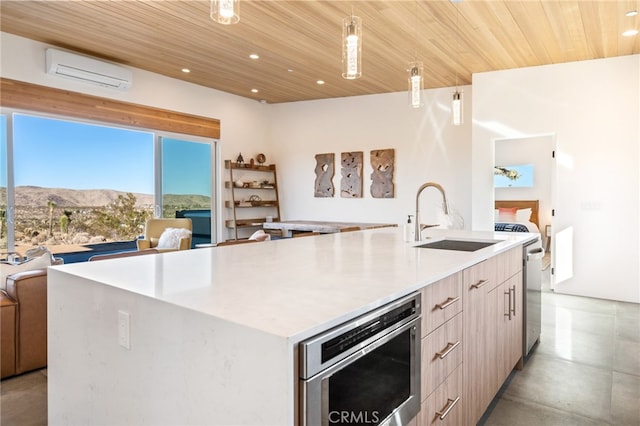 kitchen with a wall mounted AC, a large island with sink, wooden ceiling, a mountain view, and sink