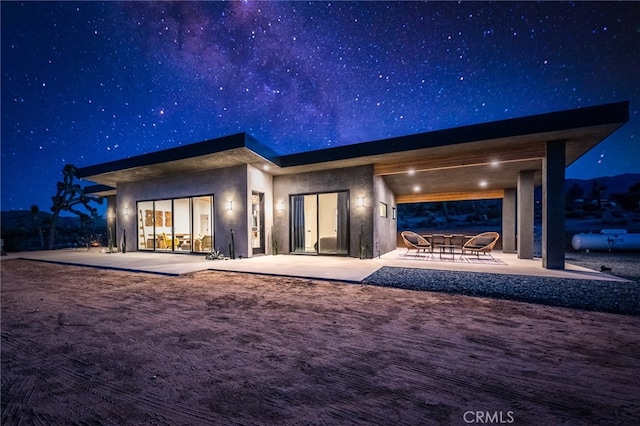 back house at twilight featuring a patio area