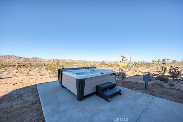 view of patio featuring a hot tub and a mountain view