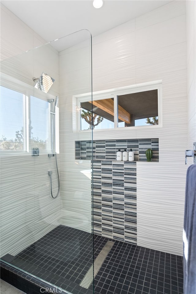 bathroom featuring a tile shower, tile walls, and tile patterned flooring