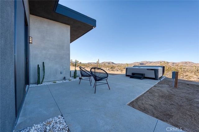 view of patio / terrace featuring a hot tub and a mountain view