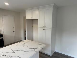 kitchen with light stone counters, dark hardwood / wood-style flooring, and white cabinets