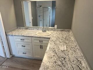 bathroom with hardwood / wood-style floors, vanity, and a shower with door