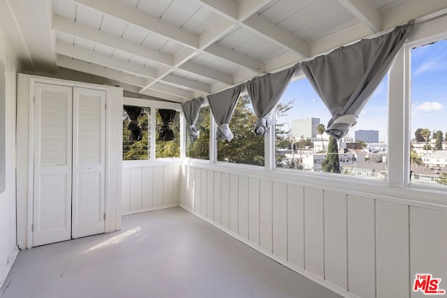 unfurnished sunroom featuring lofted ceiling with beams and a healthy amount of sunlight