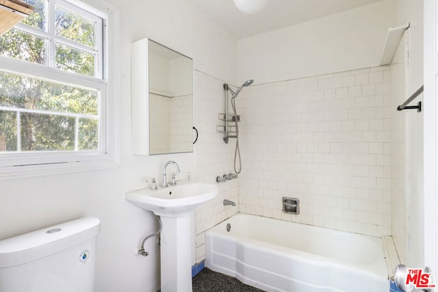 full bathroom featuring toilet, a healthy amount of sunlight, tiled shower / bath combo, and sink