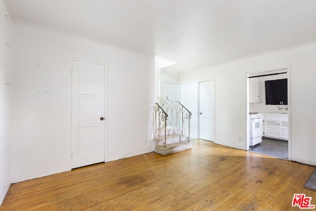 unfurnished room featuring hardwood / wood-style floors and sink