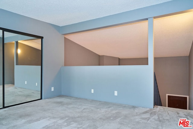 unfurnished room featuring carpet floors, lofted ceiling with beams, and a textured ceiling