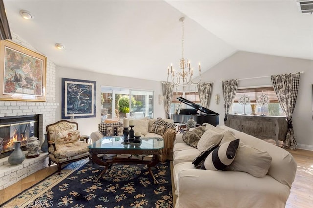 living room with a fireplace, light wood-type flooring, an inviting chandelier, and lofted ceiling