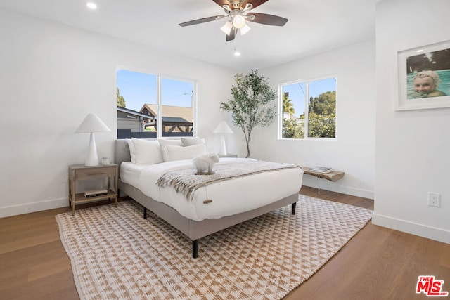 bedroom featuring ceiling fan, light hardwood / wood-style floors, and multiple windows