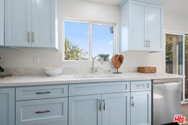 kitchen featuring stainless steel dishwasher, sink, and light stone counters