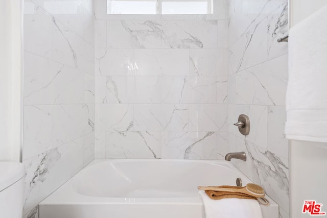 bathroom featuring toilet and tiled shower / bath