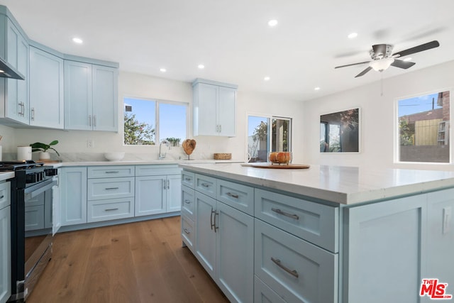 kitchen with light stone countertops, wood-type flooring, range, and a wealth of natural light