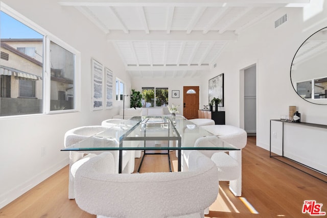 dining room with vaulted ceiling with beams, light hardwood / wood-style flooring, and a healthy amount of sunlight