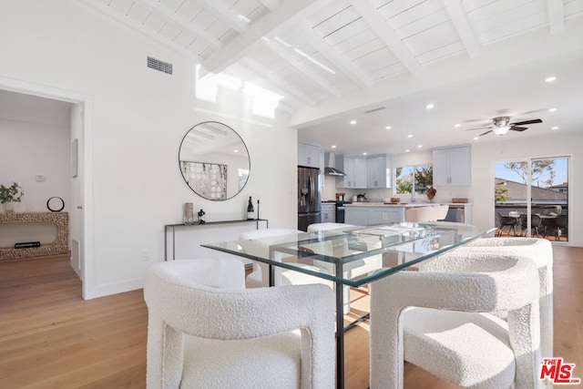 dining area with ceiling fan, vaulted ceiling with beams, light hardwood / wood-style flooring, and wooden ceiling