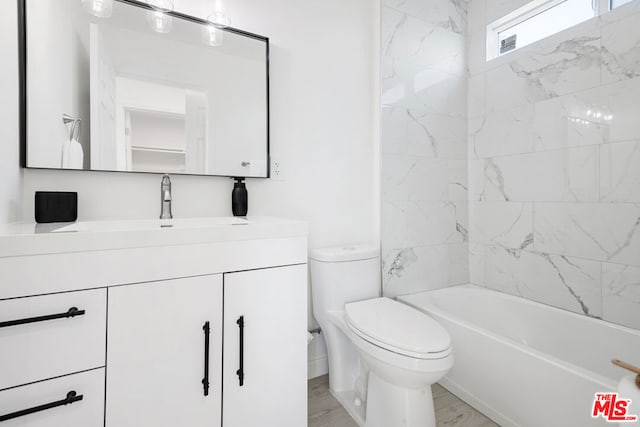 full bathroom with hardwood / wood-style flooring, tiled shower / bath combo, vanity, and toilet