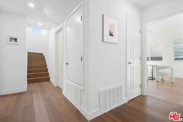 corridor with lofted ceiling and hardwood / wood-style floors