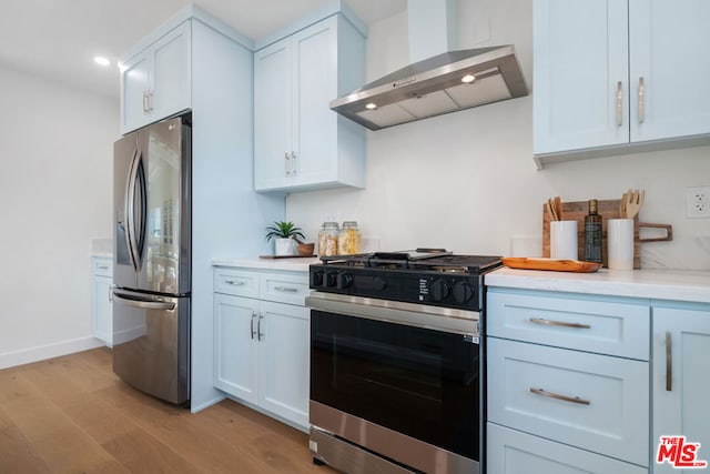 kitchen with stainless steel refrigerator with ice dispenser, gas range, wall chimney exhaust hood, and white cabinets