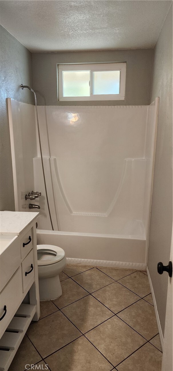 full bathroom with toilet, tile patterned flooring, bathtub / shower combination, vanity, and a textured ceiling