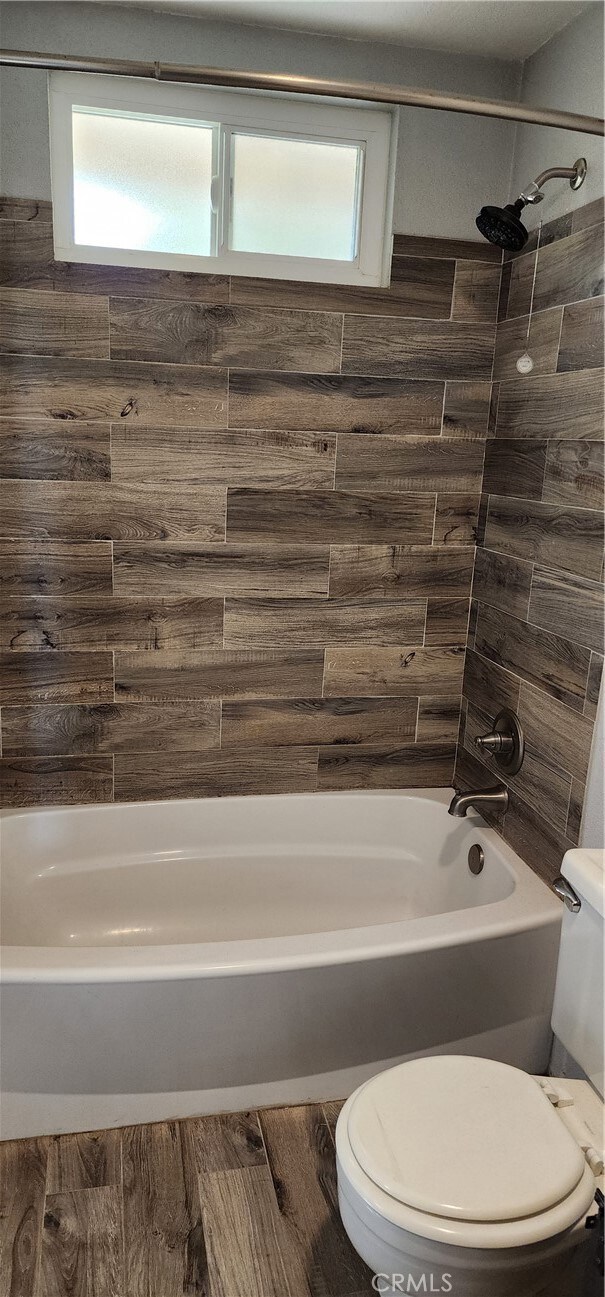 bathroom with toilet and tiled shower / bath combo