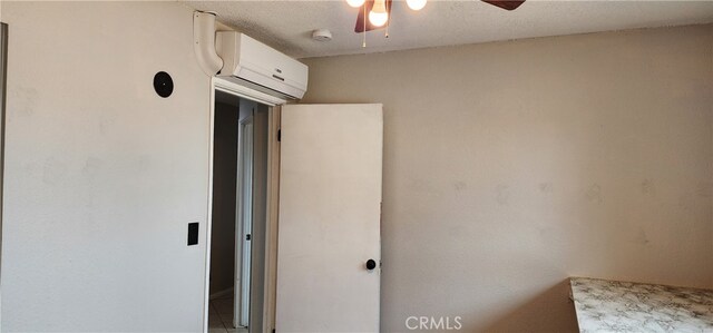 interior space featuring ceiling fan, a textured ceiling, and a wall unit AC