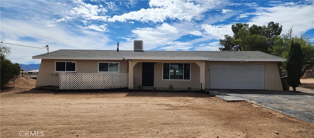 ranch-style house with central air condition unit and a garage